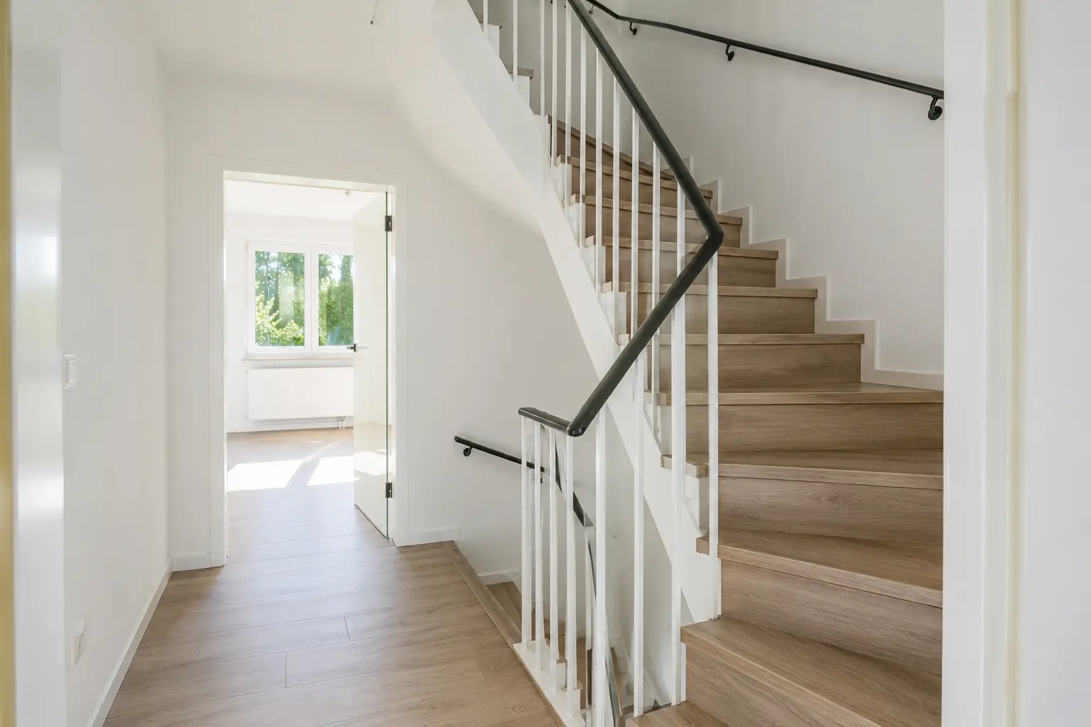 Treppenhaus mit Holztreppe und hellem Flur