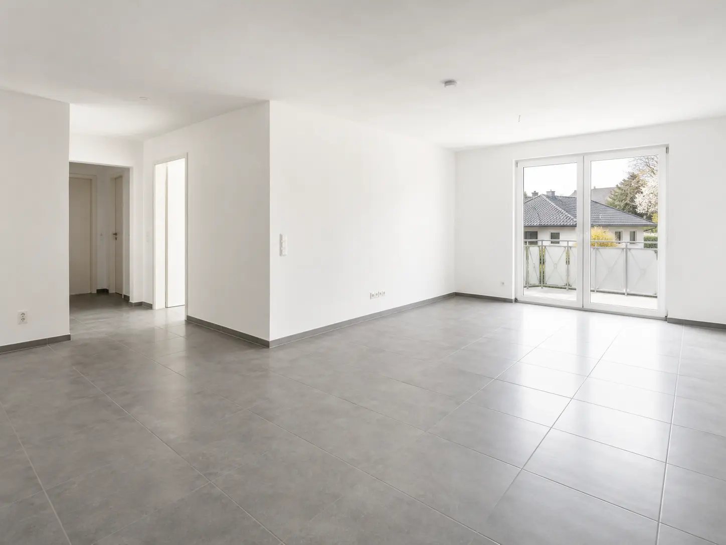 Helles Wohnzimmer mit Balkontür und grauen Fliesen einer Doppelhaushälfte zur Miete in Adelsdorf