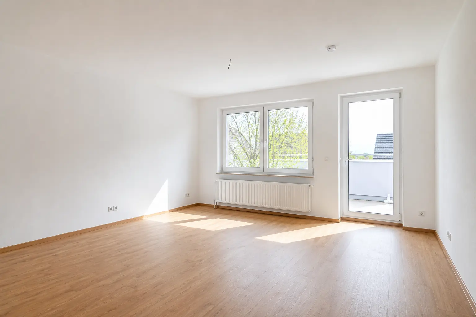 Wohnzimmer mit Balkontür und Laminatboden einer Dreizimmerwohnung zur Miete in Höchstadt an der Aisch